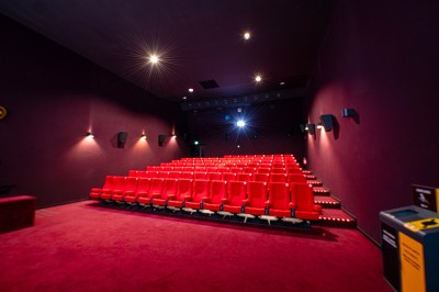 Rangée de fauteuils rouges numérotés dans une salle de cinéma sombre.