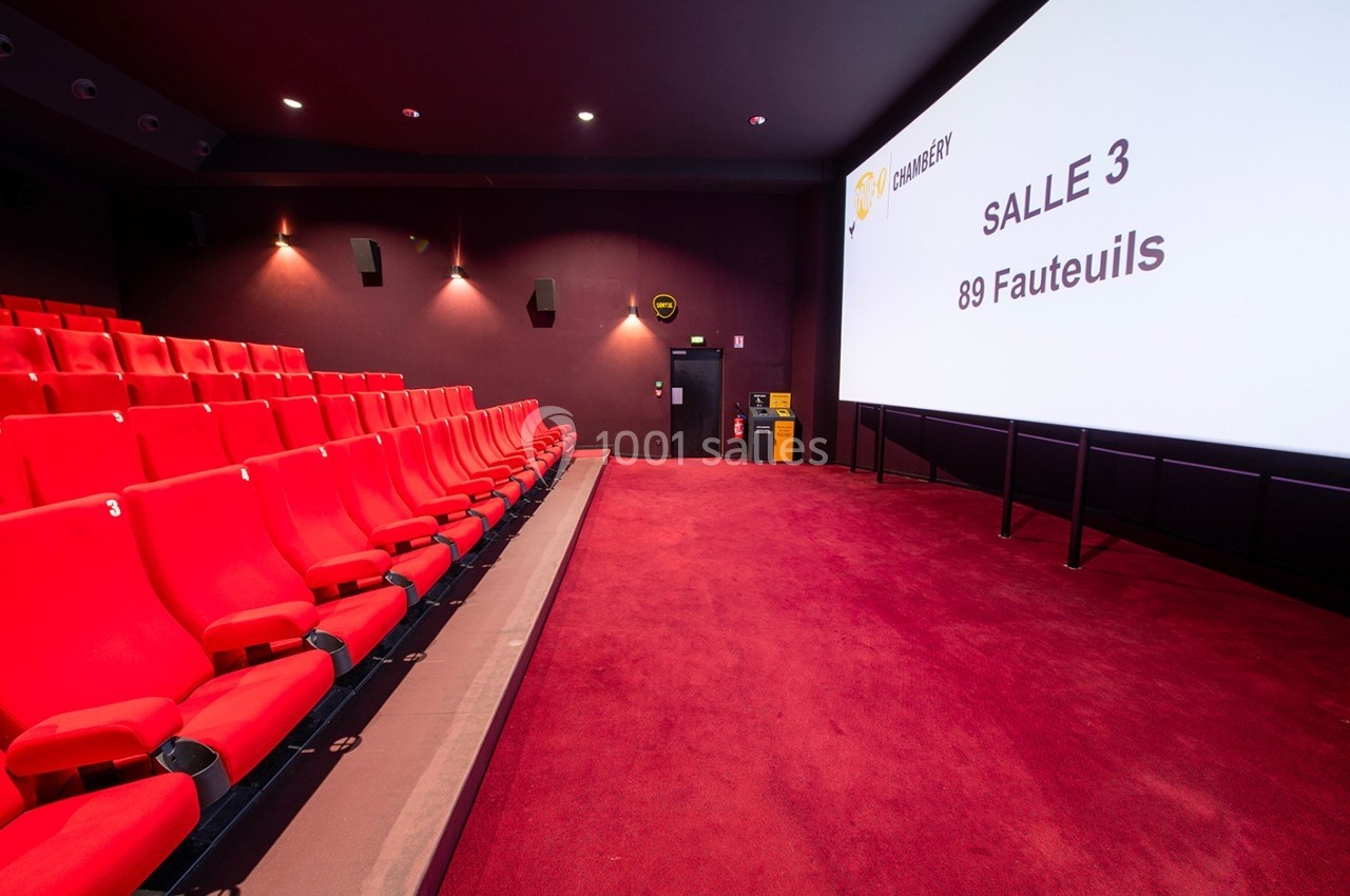 Salle de cinéma vide avec des rangées de fauteuils rouges et un écran affichant ’Salle 3, 89 fauteuils’.