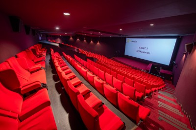 Rangée de fauteuils rouges numérotés dans une salle de cinéma sombre.
