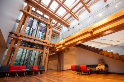 Silhouette d'un coq noir sur une rambarde en bois devant un mur blanc avec le logo jaune ’Pathé !’ éclairé par la lumière.