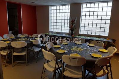 Un petit pont en bois traverse un bassin entouré de végétation, avec une route et des bâtiments en arrière-plan.