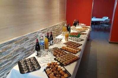 Un petit pont en bois traverse un bassin entouré de végétation, avec une route et des bâtiments en arrière-plan.