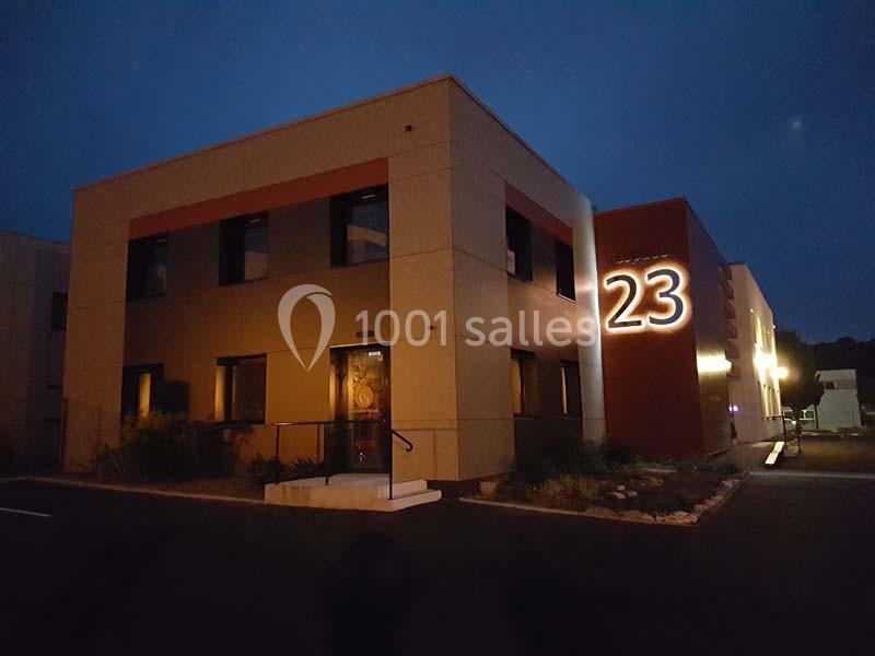 Bâtiment moderne éclairé de nuit avec le numéro 23 lumineux sur la façade.