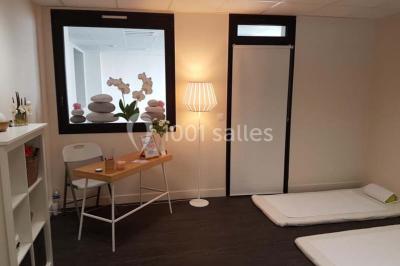 Bâtiment moderne à deux étages avec façade grise et rouge, entouré d'un parking et clôturé par une grille noire.