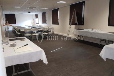 Bâtiment moderne à deux étages avec façade grise et rouge, entouré d'un parking et clôturé par une grille noire.