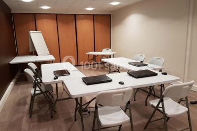 Bâtiment moderne à deux étages avec façade grise et rouge, entouré d'un parking et clôturé par une grille noire.