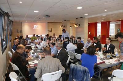 Bâtiment moderne à deux étages avec façade grise et rouge, entouré d'un parking et clôturé par une grille noire.