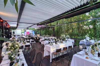 Salle de restaurant moderne avec bar central, tabourets jaunes, tables dressées et éclairage tamisé.