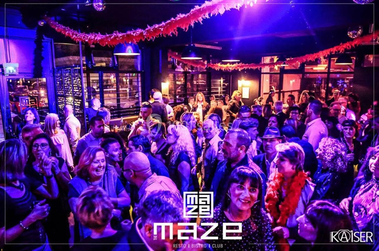 Foule dans un club décoré de guirlandes rouges, éclairé par des lumières violettes et ambiance festive.