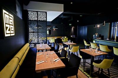 Salle de restaurant moderne avec chaises colorées, tables dressées et éclairage tamisé.