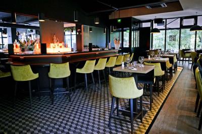 Salle de restaurant moderne avec chaises colorées, tables dressées et éclairage tamisé.