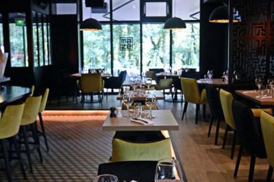 Salle de restaurant moderne avec chaises colorées, tables dressées et éclairage tamisé.