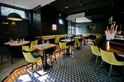 Salle de restaurant moderne avec chaises colorées, tables dressées et éclairage tamisé.