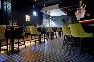 Salle de restaurant moderne avec chaises colorées, tables dressées et éclairage tamisé.