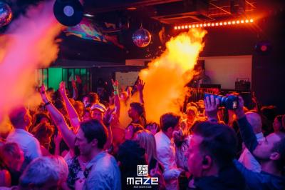 Salle de restaurant moderne avec chaises colorées, tables dressées et éclairage tamisé.