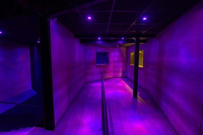 Salle de toilettes modernes avec lavabos en acier inoxydable, miroirs, cabines fermées et éclairage au plafond.