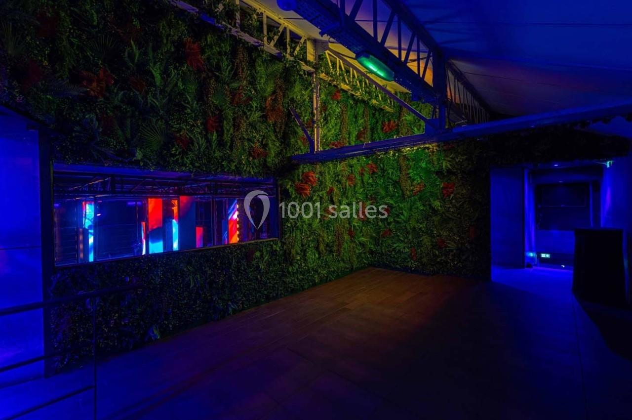 Mur végétal éclairé par des lumières colorées dans un espace intérieur à l'ambiance tamisée et moderne.