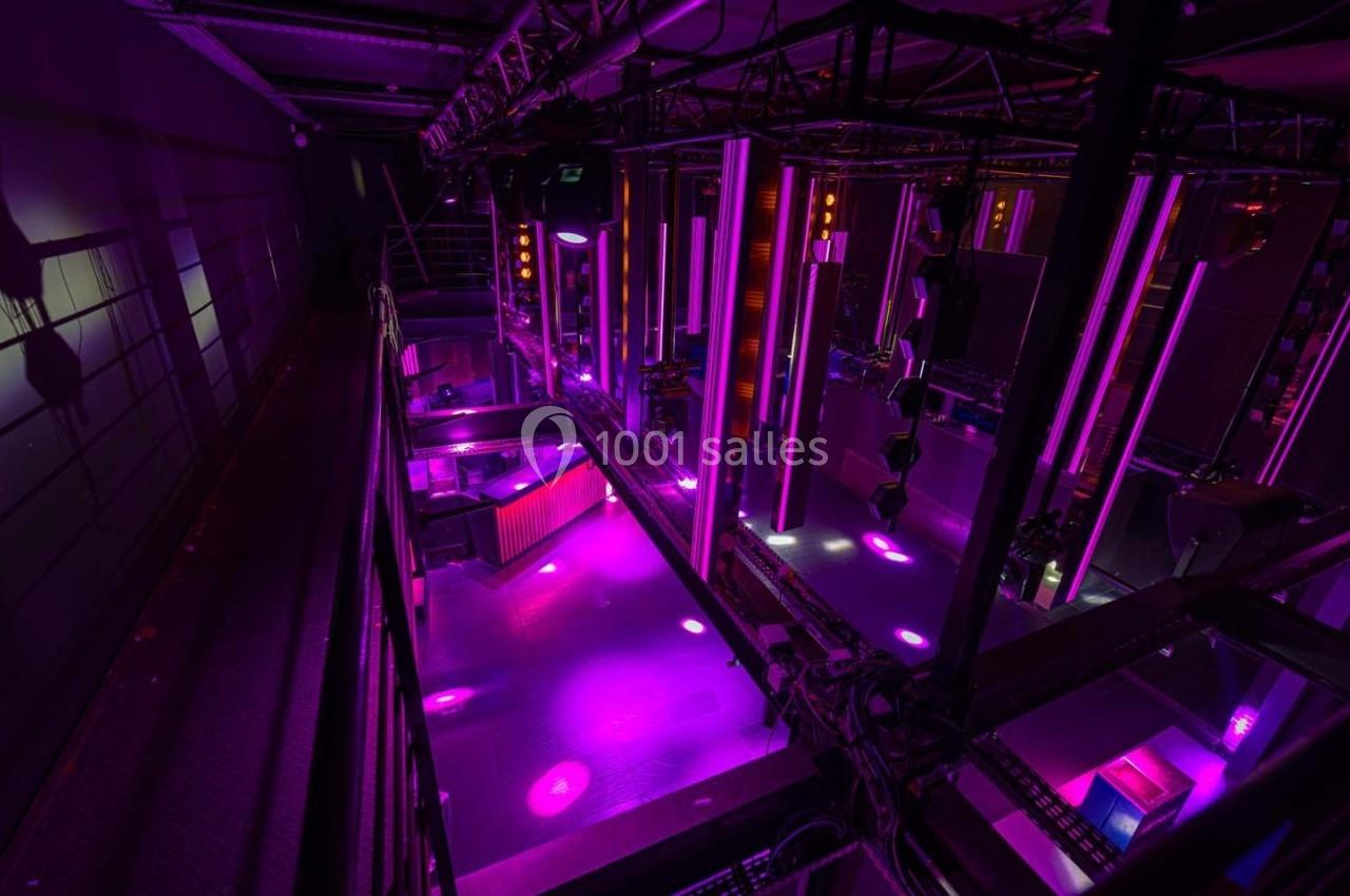 Vue plongeante d'une salle équipée de lumières violettes et de structures métalliques pour des événements ou spectacles.