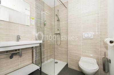 Chambre lumineuse avec lit double, décor beige et fenêtre ouverte offrant une vue sur la mer et les collines.