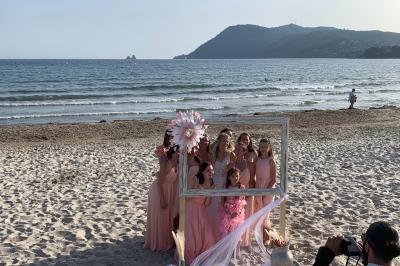 Chambre lumineuse avec lit double, décor beige et fenêtre ouverte offrant une vue sur la mer et les collines.