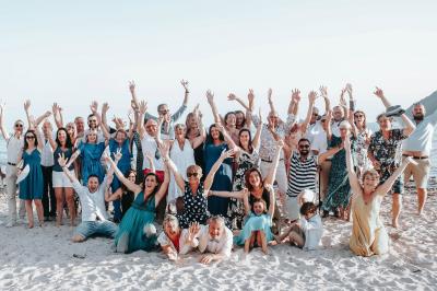 Chambre lumineuse avec lit double, décor beige et fenêtre ouverte offrant une vue sur la mer et les collines.