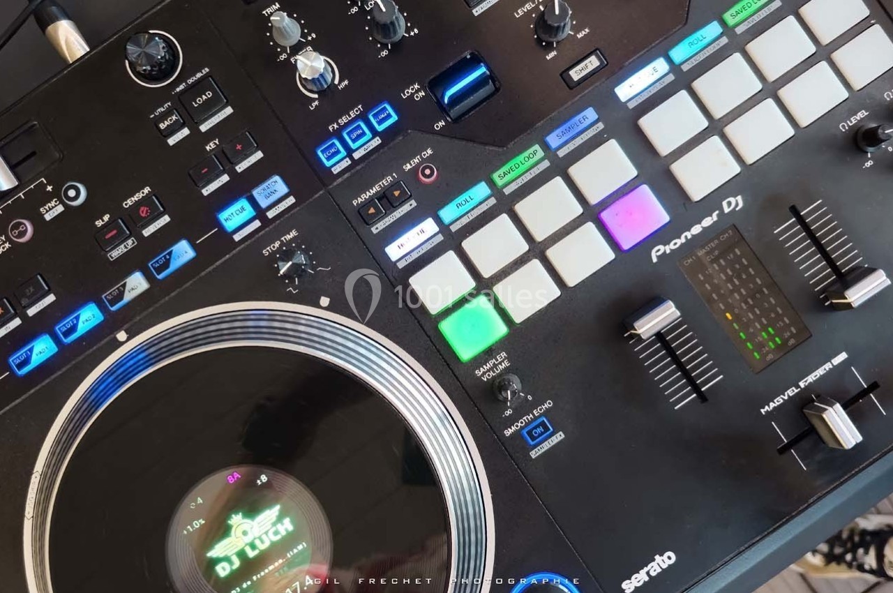 Table de mixage DJ avec platine vinyle, pads lumineux, boutons de contrôle et égaliseur visible.