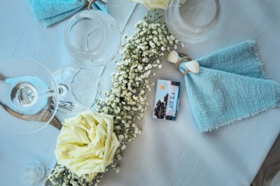 Chambre lumineuse avec lit double, décor beige et fenêtre ouverte offrant une vue sur la mer et les collines.