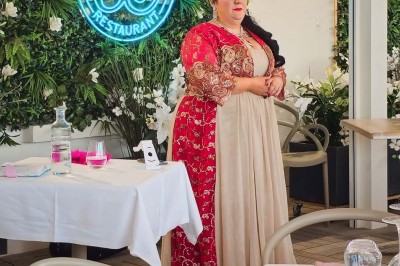 Chambre lumineuse avec lit double, décor beige et fenêtre ouverte offrant une vue sur la mer et les collines.