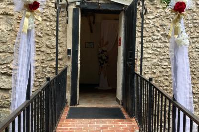 Tentes blanches installées sur une pelouse entourée d'arbres, avec tables et bottes de foin disposées en extérieur.