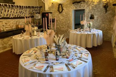 Tentes blanches installées sur une pelouse entourée d'arbres, avec tables et bottes de foin disposées en extérieur.