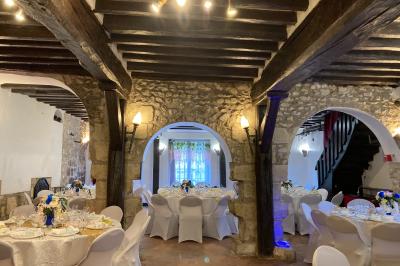 Tentes blanches installées sur une pelouse entourée d'arbres, avec tables et bottes de foin disposées en extérieur.