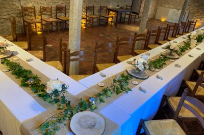 Tentes blanches installées sur une pelouse entourée d'arbres, avec tables et bottes de foin disposées en extérieur.