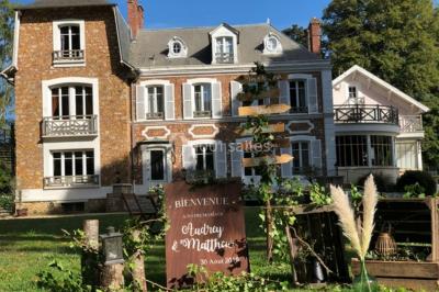 Maison en briques et crépi avec jardin, panneau de bienvenue pour un mariage au premier plan.