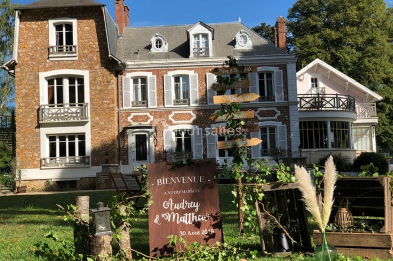 Maison en briques et crépi avec jardin, panneau de bienvenue pour un mariage au premier plan.