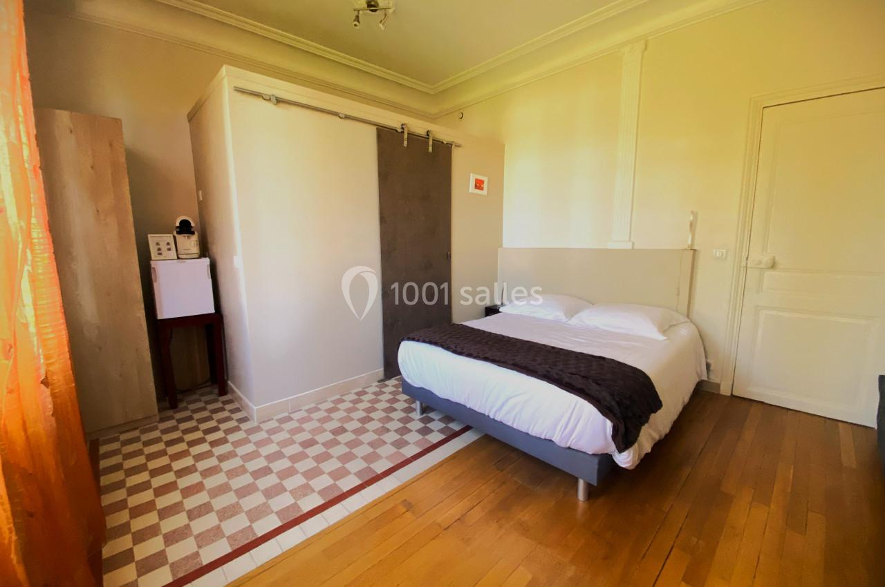 Chambre avec lit double, parquet, salle d'eau attenante avec porte coulissante et lumière naturelle.