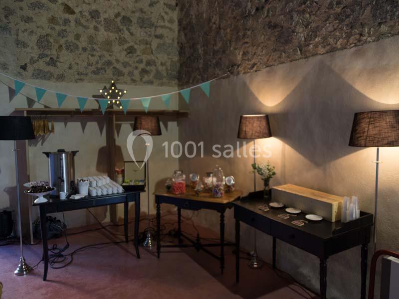 Buffet avec boissons chaudes, bonbonnières et vaisselle, installé dans une pièce aux murs en pierre et éclairée par des…