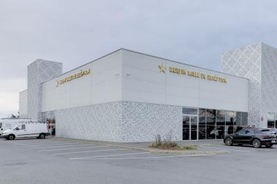 Bâtiment moderne avec façade grise, enseigne ’Bérénice Salle de Réception’, parking avec quelques véhicules.