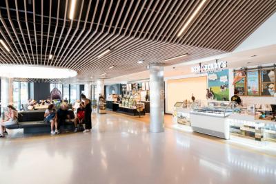 Terrasse d'un café Starbucks devant un immeuble moderne aux façades blanches et jaunes, sous un ciel partiellement nuageux.