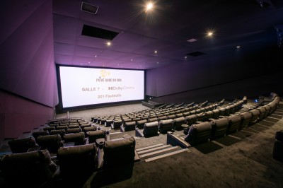 Terrasse d'un café Starbucks devant un immeuble moderne aux façades blanches et jaunes, sous un ciel partiellement nuageux.