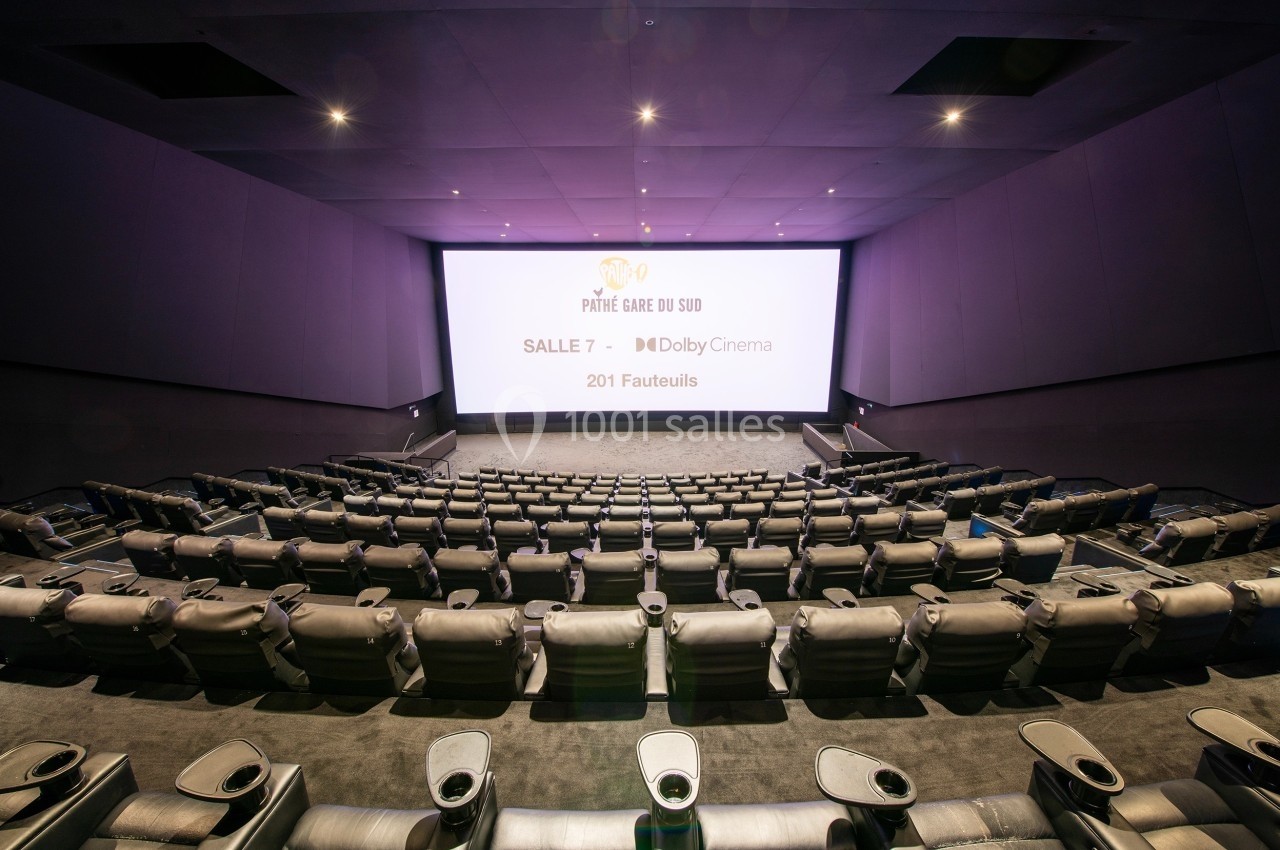 Salle de cinéma moderne avec grand écran, sièges inclinables en cuir et allée centrale.