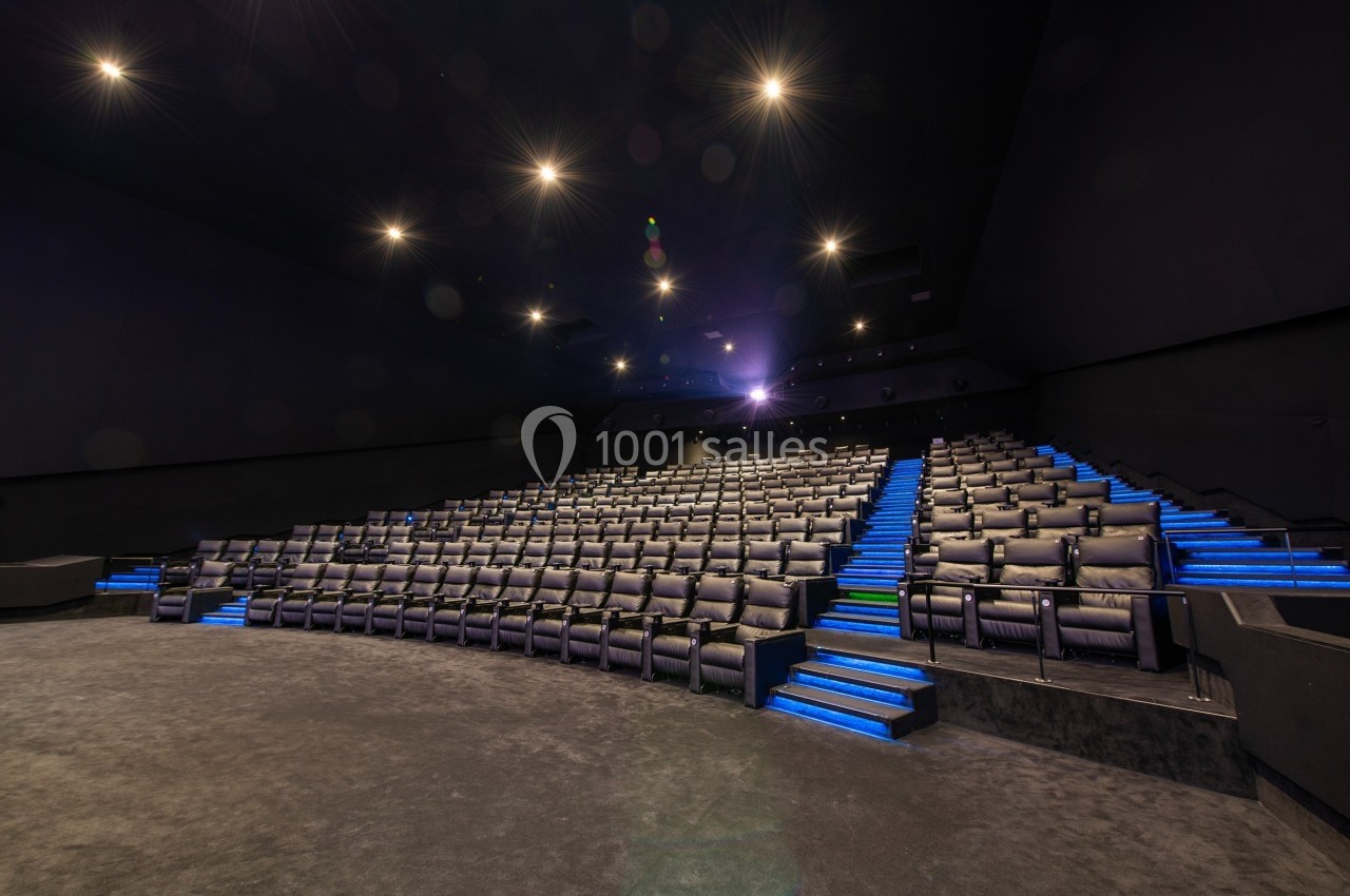 Salle de cinéma vide avec rangées de sièges noirs et éclairage bleu sur les marches.