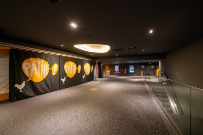 Terrasse d'un café Starbucks devant un immeuble moderne aux façades blanches et jaunes, sous un ciel partiellement nuageux.