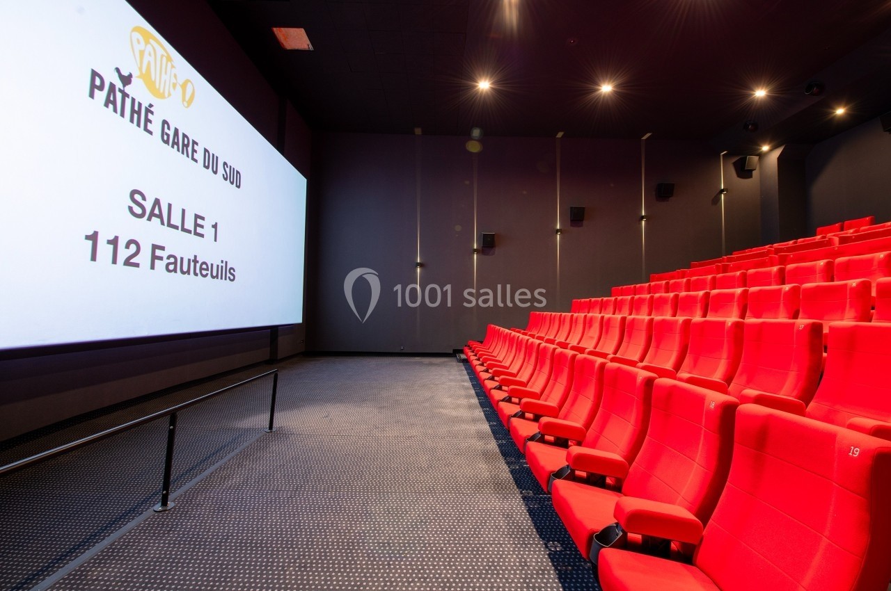 Salle de cinéma moderne avec sièges rouges alignés et écran blanc affichant ’Pathé Gare du Sud, Salle 1, 112 fauteuils’.