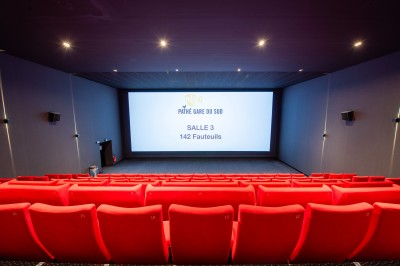 Terrasse d'un café Starbucks devant un immeuble moderne aux façades blanches et jaunes, sous un ciel partiellement nuageux.