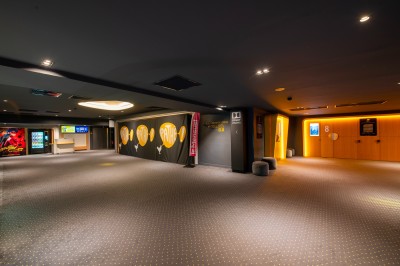 Miniature Espace Cocktail Salle de cinéma vide avec des rangées de sièges rouges, éclairée par des spots au plafond.