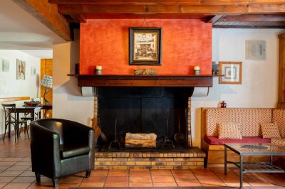 Maison recouverte de lierre avec volets bleus, entourée de végétation dense et montagnes en arrière-plan.