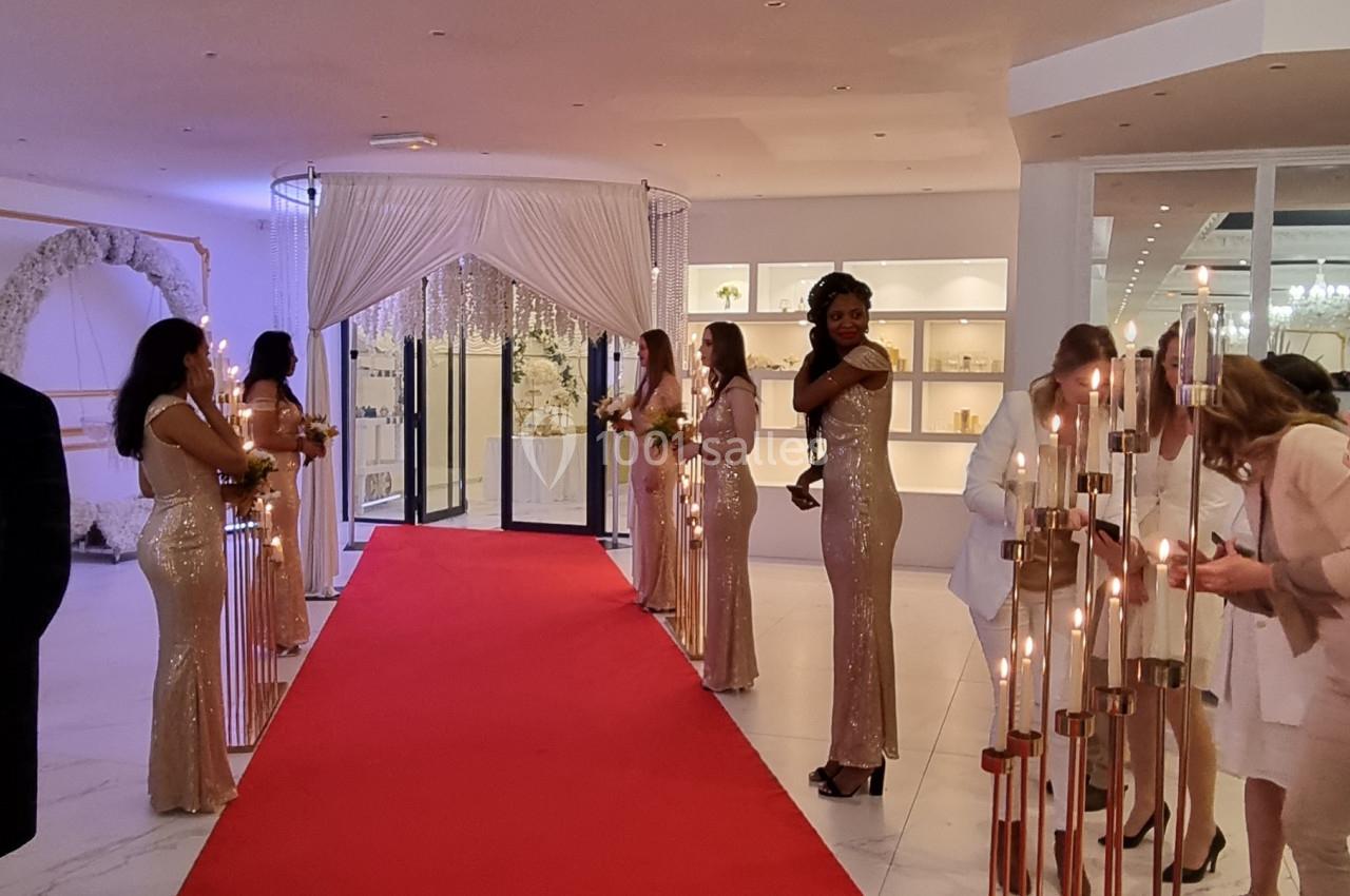 Des hôtesses en robes dorées alignées le long d'un tapis rouge dans un espace intérieur élégant.