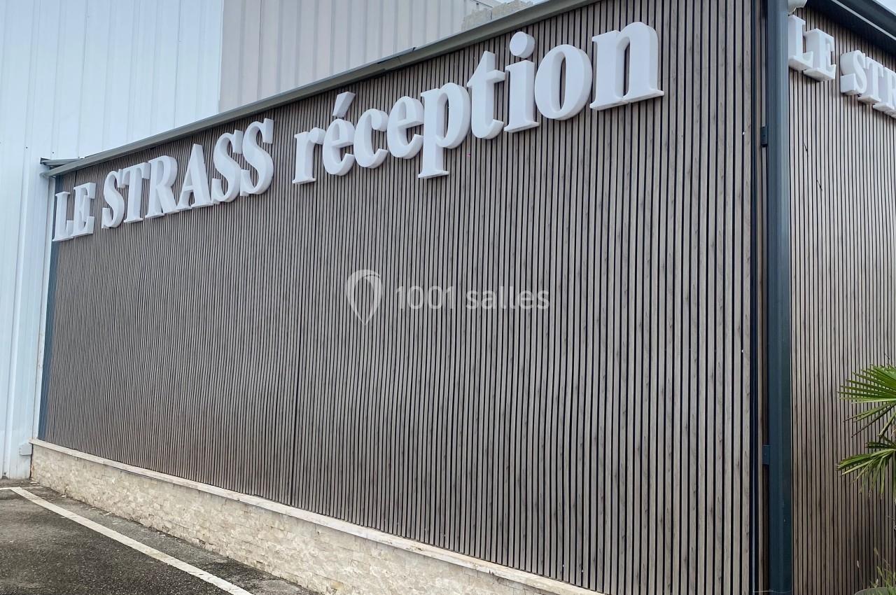 Façade d'un bâtiment avec l'inscription ’Le Strass réception’ sur un revêtement en bois vertical.
