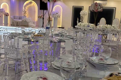 Table de mariage décorée de fleurs blanches et roses, avec deux chaises et un panneau ’Mr & Mrs’ au centre.