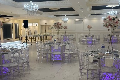 Table de mariage décorée de fleurs blanches et roses, avec deux chaises et un panneau ’Mr & Mrs’ au centre.